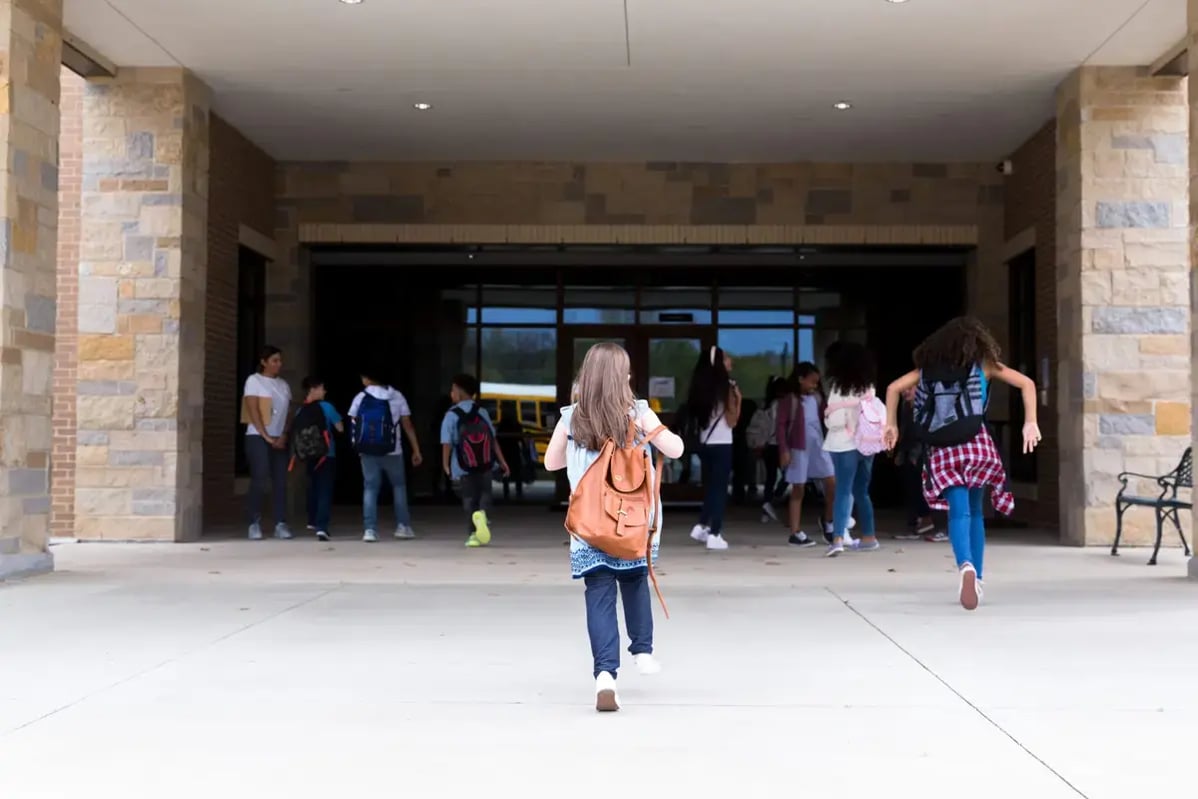 A middle school student walks into school with her backpack on (Photo SDI ProductionsiStock)